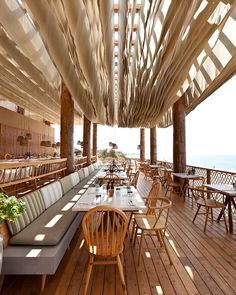 an outdoor dining area with wooden tables and benches on the deck overlooking the ocean,