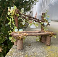 a wooden bench made out of branches with flowers growing on it's back end