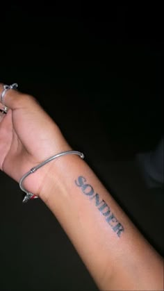 someone is holding their wrist with the word sonder tattooed on it's arm