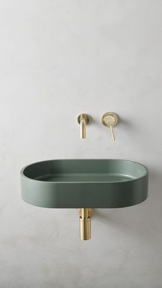 an oval sink with gold faucet and green basin