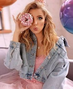 a woman in a pink dress holding a doughnut up to her face