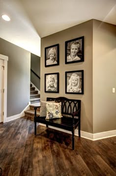 a room with pictures on the wall and a bench in front of it next to stairs