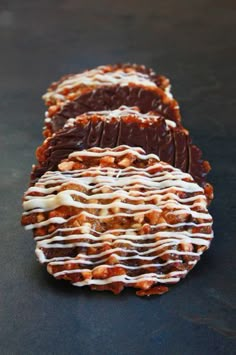 three pieces of chocolate covered pretzels on a black surface with white icing