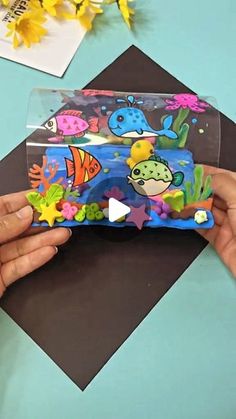 someone is holding a plastic case with fish and sea animals on it