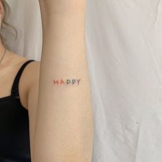 a woman's arm with the word happy tattooed on her left arm, in red and blue ink