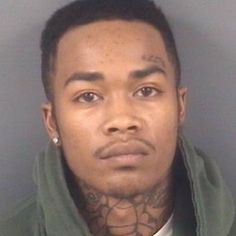 a man with tattoos on his neck is looking at the camera while wearing a green hoodie