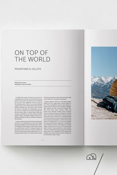 an open book with a man sitting on the ground in front of snow covered mountains