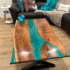 a wooden table sitting on top of a hard wood floor next to a black couch