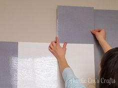 a woman is painting the wall with white and gray paint on it's walls