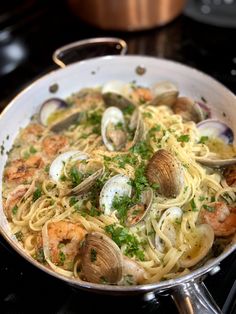 a pan filled with pasta and clams on top of a stove