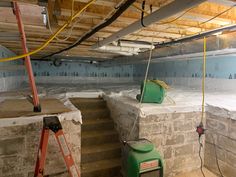 an unfinished basement with several buckets and ladders on the wall, some being filled with water