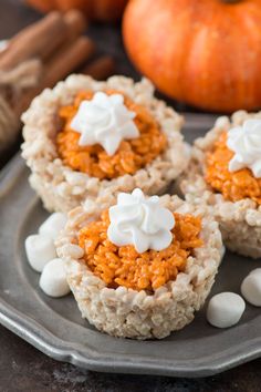 rice krispy treats with marshmallows are on a plate next to pumpkins