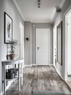 an empty hallway with white walls and wood floors is seen in this image from the front door