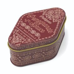 a red and gold tin with an ornate design on the lid, sitting in front of a white background