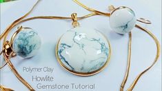 two white and blue marble pendants sitting on top of a table next to a gold chain