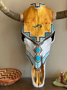 a cow's head is adorned with gold, turquoise and white designs on it