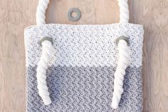 a crocheted bag hanging from a hook on a wooden wall with two handles