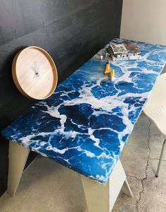 a table with blue and white paint on it, next to a clock that is sitting on the wall