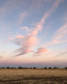 an empty field with some clouds in the sky