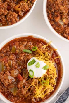 three white bowls filled with chili and cheese