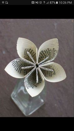 an origami flower made out of book pages in a glass vase on a table