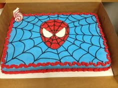 a birthday cake decorated with a spiderman face on top of a cardboard box for someone's 5th birthday