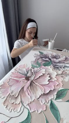 a woman is painting flowers on a table