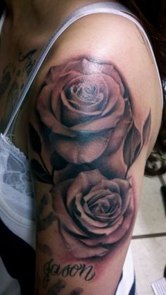 a woman's half sleeve with three roses on her arm and shoulder, all done in black and grey