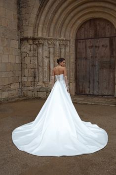 a woman in a white wedding dress is standing outside an old building with stone arches