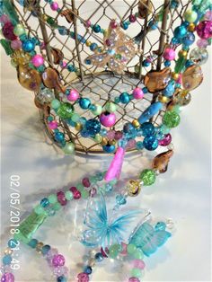 a wire basket filled with lots of different colored beads and glass bead necklaces