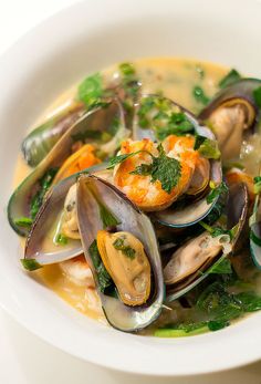 a white bowl filled with clams and greens