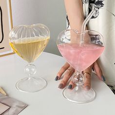 two wine glasses sitting on top of a table next to each other, one filled with liquid