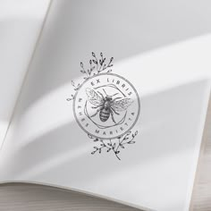 an open book with a drawing of a bee on it's cover and the words ex libri written in black ink