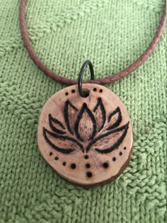 a wooden pendant with a flower on it sitting on a green cloth covered tablecloth