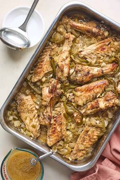 a pan filled with chicken and onions next to a spoon