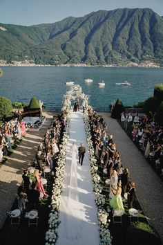 an outdoor wedding ceremony on the shores of lake comoni, with mountains in the background