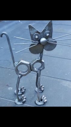 a metal cat sculpture sitting on top of a sidewalk