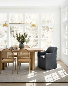 a dining room table and chairs in front of large windows