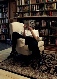 a woman sitting in a chair reading a book