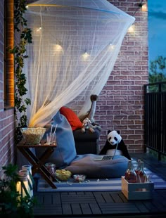 a panda bear sitting on top of a chair under a canopy