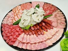 an assortment of meats and vegetables are arranged on a platter with white flowers