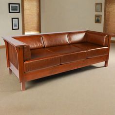 a brown leather couch sitting in a living room next to a wooden framed painting on the wall