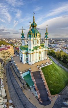 an aerial view of a church in the middle of a city with tall buildings and green roofs