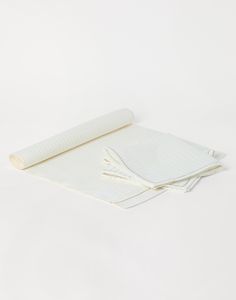 a roll of white paper sitting on top of a table next to a rolled up piece of cloth