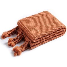 a brown knitted blanket folded on top of each other with tasselled ends