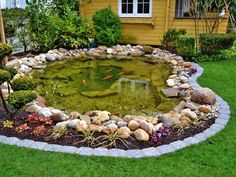 a fish pond in the middle of a garden with rocks and gravel around it, surrounded by grass