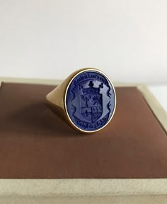 Lapis Lazuli Coat of Arms Signet Ring that can be personalized with your desired Family Crest design. A handmade piece that has been brought to life with the combination of fine goldsmith techniques and the latest technology. 📩 Leave us a message with your custom personalization, your family crest, coat of arms, logo or any design imagined. If you would like a different gemstone instead, please contact us. Lapis Lazuli Signet Ring - Coat of Arms Ring - Armorial Ring - Wax Seal Ring - Family Cre Heirloom Oval Ring For Commemoration, Blue Engraved Signet Ring As Gift, Engraved Blue Signet Ring As Gift, Oval 14k Stamped Commemorative Rings, Round Jewelry With Coat Of Arms For Gifts, Oval 14k Gold Commemorative Rings, Oval 14k Stamped Commemoration Ring, Symbolic Blue Ring For Anniversary, Blue Intaglio Ring As Gift