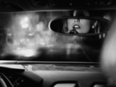 a woman's reflection in the rear view mirror of a car