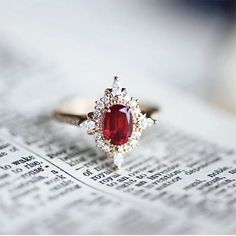 a red stone ring sitting on top of an open newspaper