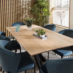 a dining room table with blue chairs and a plant in the center on top of it